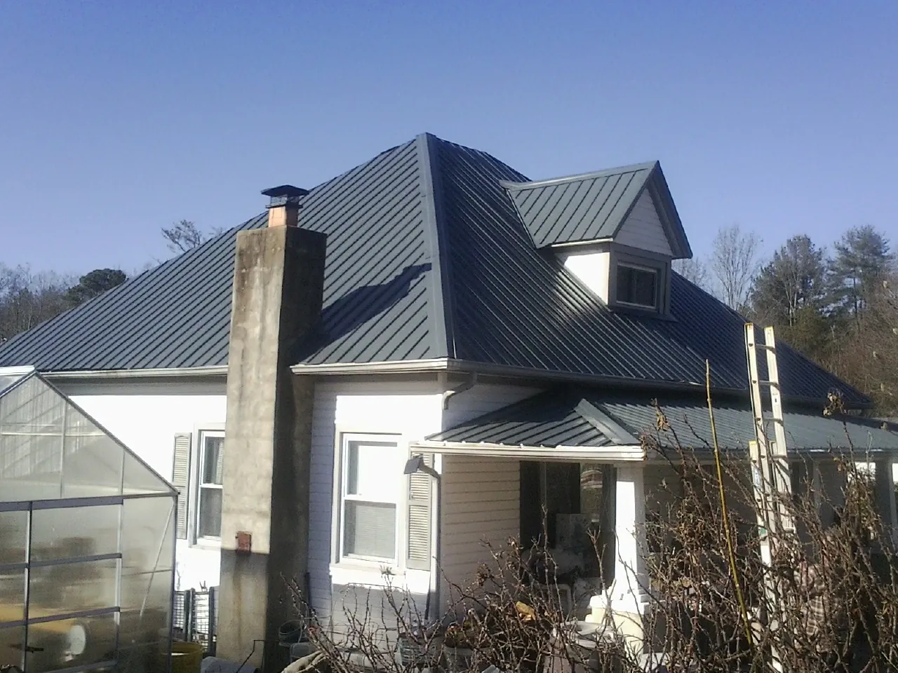 Dark blue standing seam metal roof on a white farmhouse with dormer — Slate & Tile Roof Repair by Roofing Brothers in Thomaston