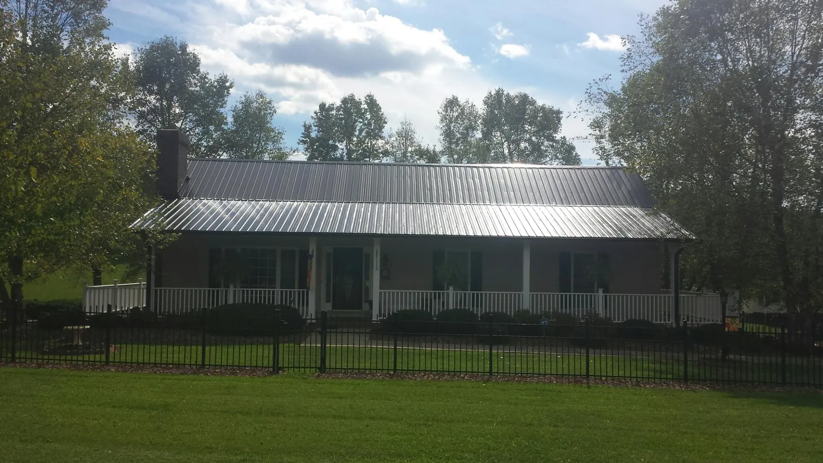 Gray metal roof on a brick ranch with a full width front porch — Gutter Guard Installation work by our crew in Thomaston